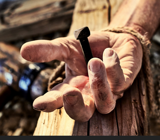 A hand holding a nail Description automatically generated